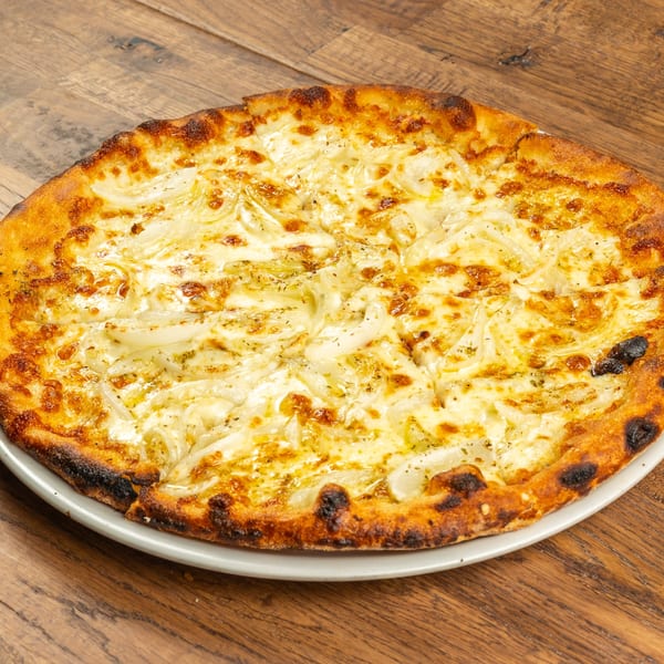 Tutto Pizza & Pasta's white pizza with caramelized onions and melted cheese on a wooden table.