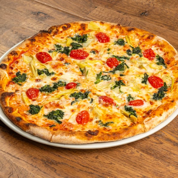Tutto Pizza & Pasta's pizza with spinach, artichoke hearts, and cherry tomatoes on a wooden table.