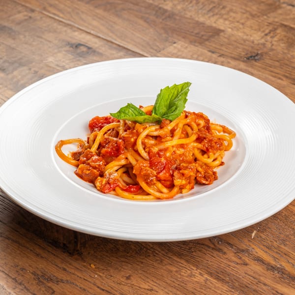 Spaghetti with rich red bolognese sauce and fresh basil on a white plate.